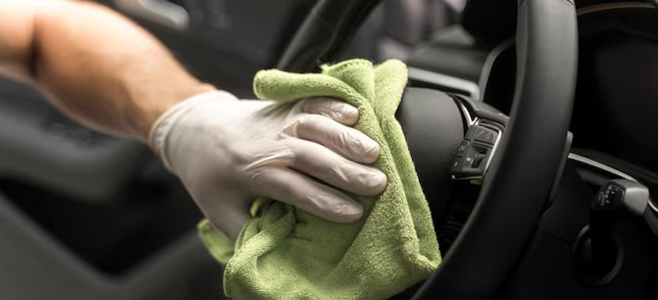 Detailing specialist rinsing soap from a dark sedan in a Springfield driveway